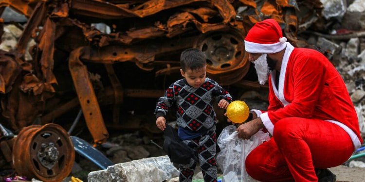 Un giovane iracheno vestito da Babbo Natale distribuisce regali nella città vecchia di Mosul (LaPresse)