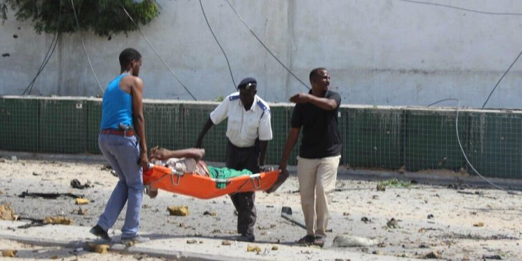 (160731) -- MOGADISHU, July 31, 2016 (Xinhua) -- People carry a wounded person after a car bomb explosion in Mogadishu, capital of Somalia, on July 31, 2016. At least five people were killed and several others were injured on Sunday in twin car bomb blasts at the headquarters of Somalia's Criminal Investigations Department (CID) in the capital city of Mogadishu. (Xinhua/Faisal Isse)(zy)