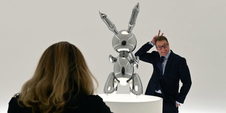 A man poses next to Jeff Koons' "Rabbit" from the Masterpieces from The Collection of S.I. Newhouse at Christie's New York press preview on May 3, 2019 as part of Christie's Post-War and Contemporary Art evening sale. (Photo by TIMOTHY A. CLARY / AFP) / RESTRICTED TO EDITORIAL USE - MANDATORY MENTION OF THE ARTIST UPON PUBLICATION - TO ILLUSTRATE THE EVENT AS SPECIFIED IN THE CAPTION