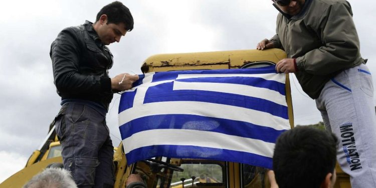 Local residents hang the Greek flag at a roadblock in Karava, on the northeastern Aegean island of Lesbos, Greece, Thursday, Feb. 27, 2020. Greece's government hoped to defuse tensions after protests over plans for new migrant camps on two of its islands Wednesday turned into violent clashes between police and local residents, some armed with Molotov cocktails and shotguns.(AP Photo/Michael Varaklas)