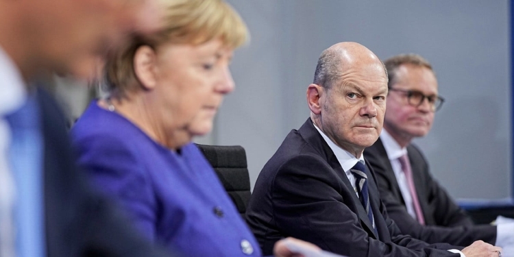 Federal Finance Minister Olaf Scholz, second right, looks at German Chancellor Angela Merkel, during a news conference in Berlin, Thursday, Nov. 18, 2021. German lawmakers have approved new measures to rein in record coronavirus infections after the head of Germany’s disease control agency warned the country could face a “really terrible Christmas.” The measures passed in the Bundestag on Thursday includes requirements for employees to prove they are vaccinated, recovered from COVID-19 or have tested negative for the virus in order to access communal workplaces. (Michael Kappeler, Pool via AP)