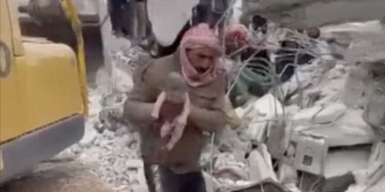 A Jandairis (Siria) un uomo tiene in braccio la bambina appena estratta dalle macerie (foto da Youtube)