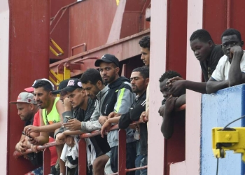 Migranti vengono fatti sbarcare da un mercantile a Salerno (Ansa)