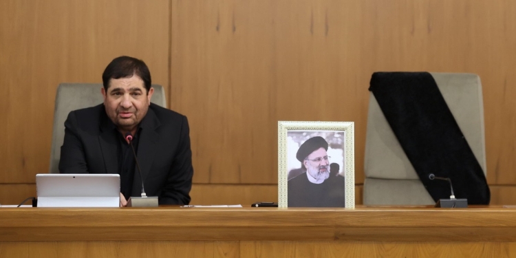 Il Presidente ad interim dell'Iran Mohammad Mokhber con una foto del defunto Presidente Ebrahim Raisi (Foto Ansa 2024 EPA/Ufficio presidenziale iraniano)