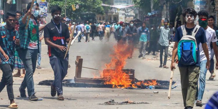 Dimostranti accendono un fuoco mentre si scontrano con la polizia durante le proteste studentesche in Bangladesh (Foto Ansa 2024 EPA/MONIRUL ALAM)