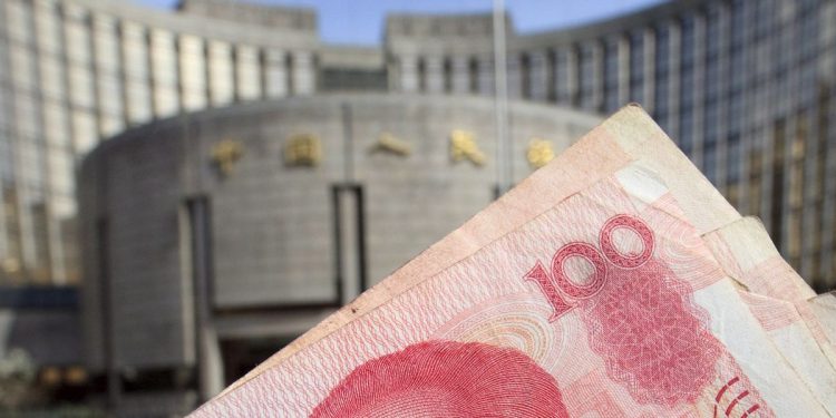 Banconota da 100 yuan renminbi. Sullo sfondo la PBOC (Ansa)