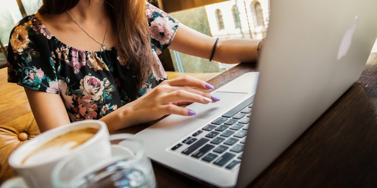 Donna che lavora al pc con tazza di caffè